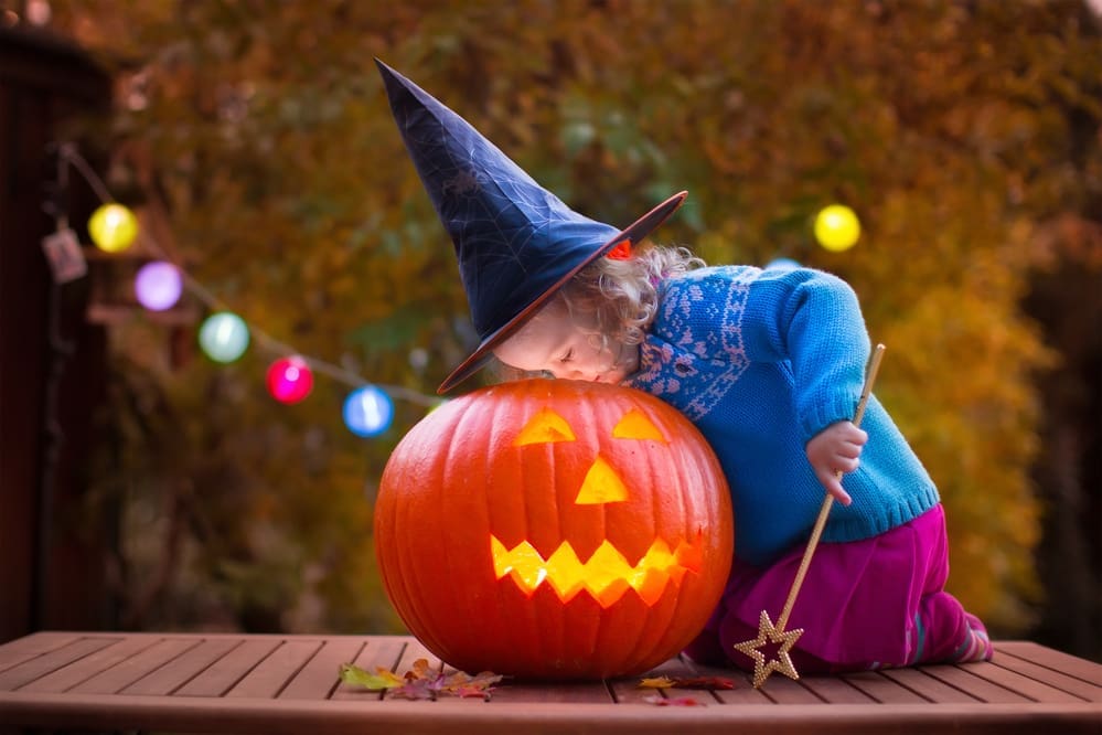 halloween pumpkin and little girl dressed as witch